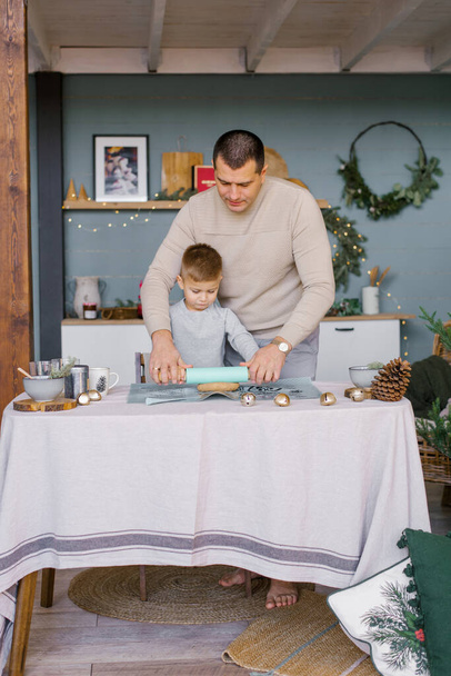 Pai e filho pequeno rolar a massa na cozinha para biscoitos de gengibre de Natal ou casa de gengibre - Foto, Imagem