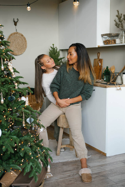 Felice famiglia mamma e figlia si divertono a prepararsi per Natale e Capodanno in cucina vicino all'albero di Natale - Foto, immagini