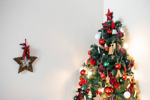 Árbol de Navidad con juguetes rojos y verdes sobre un fondo de pared claro - Foto, Imagen