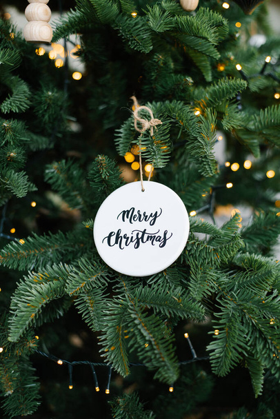 Stylish Christmas tree toy with the inscription "Merry Christmas" on the Christmas tree - Фото, изображение
