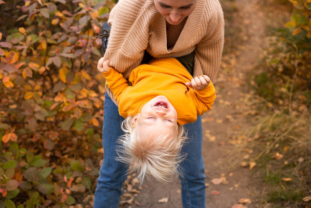Glückliche Familienmutter und kleiner Sohn spielen und lachen beim Herbstspaziergang - Foto, Bild