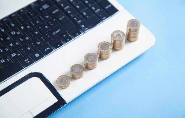Stack of coins on the laptop keyboard. - 写真・画像