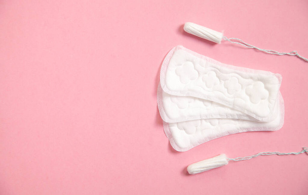 Менструальная подушка и тампоны на розовом фоне. - Фото, изображение