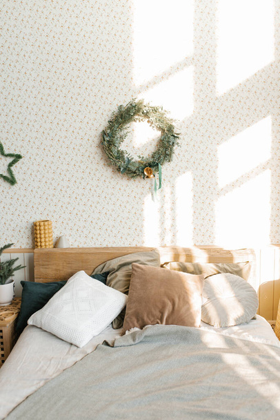 Egy ágy párnákkal és karácsonyi dekorációval a hálószobában skandináv stílusban. A ház belseje - Fotó, kép