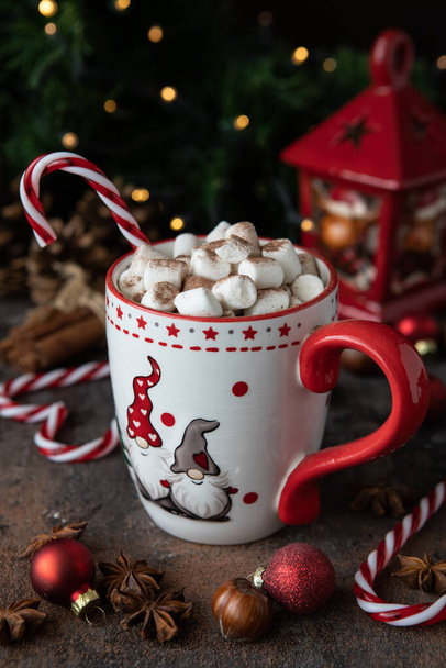 Taza roja con chocolate caliente, malvaviscos y bastón de caramelo sobre fondo oscuro para las vacaciones de Navidad - Foto, imagen