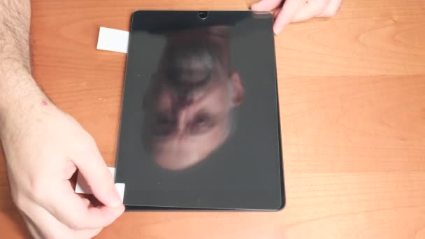 Turin, Piemont, Italien. November 2021. Installation eines Schutzglases auf einem neuen Tablet-Bildschirm. Erkennbar das reflektierte Gesicht des Technikers, der es montiert. - Filmmaterial, Video