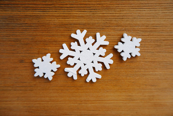 Three wooden Christmas white snowflakes on a wooden board.Natural eco-friendly Christmas decorations, Christmas rustic style, blanks for creativity, preparation for the New Year. - Photo, image