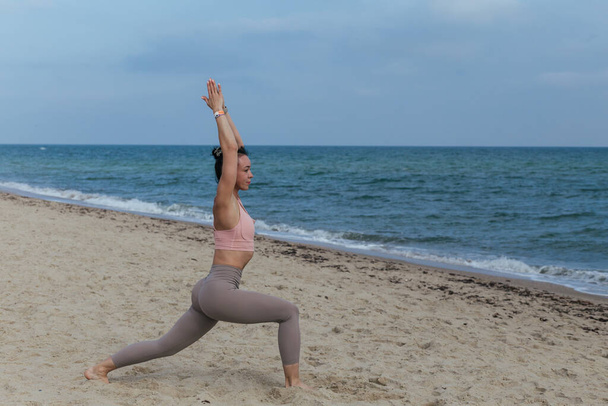 mooi jong meisje doet yoga op het strand in de buurt van de zee - Foto, afbeelding