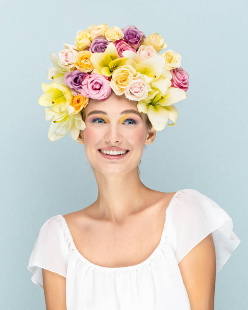Young girl gently smiles and looks into the camera lens with flowers in the head  - Photo, Image