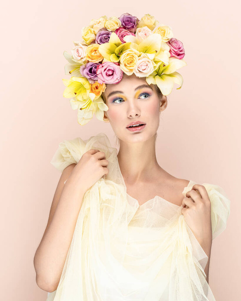 Surprised and happy young blond girl posing in studio, flowers in head - 写真・画像