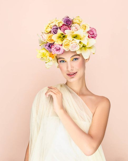 Young beautiful woman with bouquet of flower in head. Art portrait of sexy blonde with colorful flowers. Professional art makeup. Pretty pink background. Happy concept - Photo, image