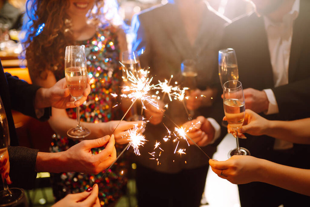 Sparkling sparklers in the hands. Playing firework to celebrate winter holidays with friends at the party. Magic New Year, Christmas. - Foto, Imagem