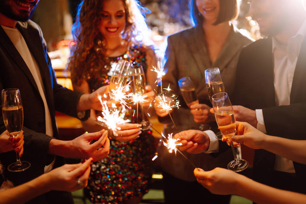 Sparkling sparklers in the hands. Playing firework to celebrate winter holidays with friends at the party. Magic New Year, Christmas. - 写真・画像