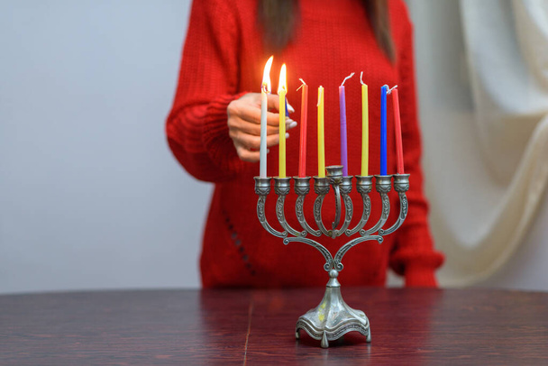 Jewish Woman lighting Hanukkah Candles in a menorah. - Fotografie, Obrázek