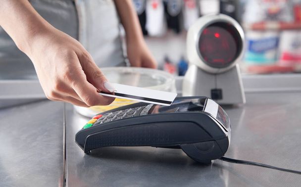 Клієнт здійснює оплату за допомогою кредитної картки в супермаркеті
. - Фото, зображення