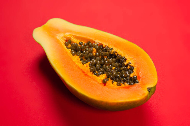Papaya fruit op een oranje achtergrond. Tropisch fruit. Halve papaja.  - Foto, afbeelding