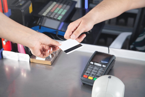 Vrouw betaalt met creditcard in supermarkt. - Foto, afbeelding