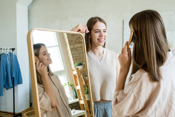 Glückliche Teenager-Zwillinge stehen vor großem Spiegel und plaudern - Foto, Bild