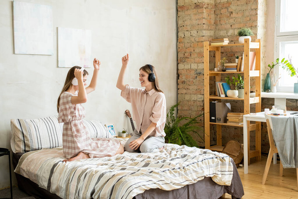 Excited teenage twin girls in headphones enjoying music - Photo, Image