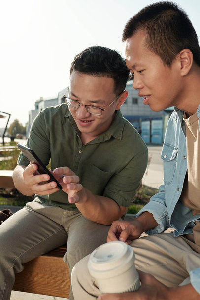 Kleine groep Chinese zakenmensen bespreken iets in smartphone - Foto, afbeelding