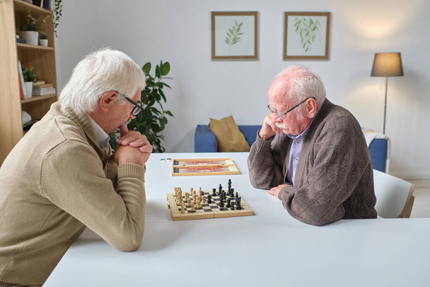 Senior men playing chess in the room - 写真・画像