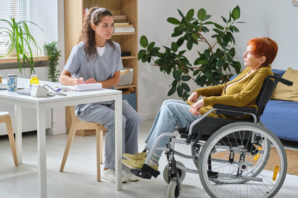 Doctor talking to senior woman with disability - Фото, зображення