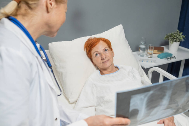 Arzt bespricht Röntgenbild mit Patient - Foto, Bild