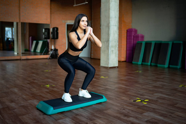 Young woman exercising in the gym, doing exercises shakes the buttocks and ass, leg lunges to the squat. fitness gym workout - Foto, Imagen