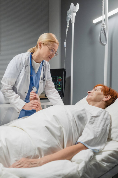 Doctor checking the pulse of senior woman in ward - Φωτογραφία, εικόνα