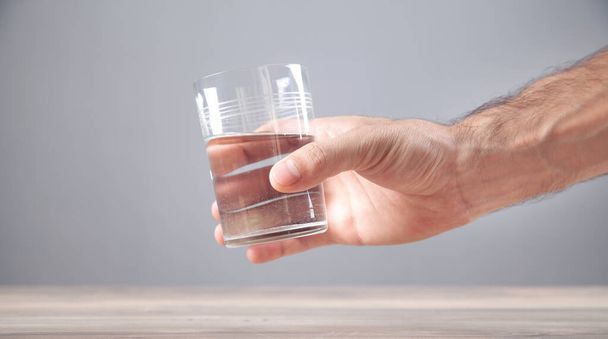 Male hand holding glass of water. - Photo, Image