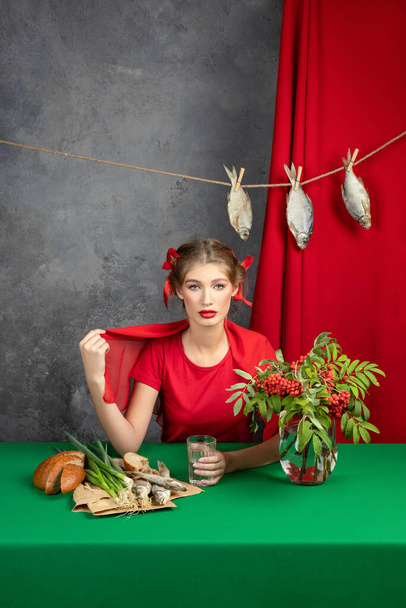 young girl in a red dress at a green table. A very positive emotion  - 写真・画像