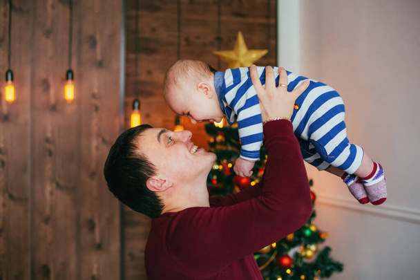 クリスマスツリーの近くで手に小さな息子と幸せな父親。友好的な家族の概念 - 写真・画像