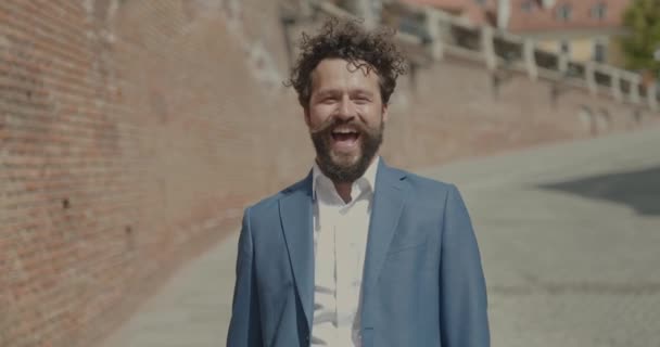 aantrekkelijke zakenman die lacht, zijn armen opent, ons iets uitlegt met opwinding en een aktetas vasthoudt - Video