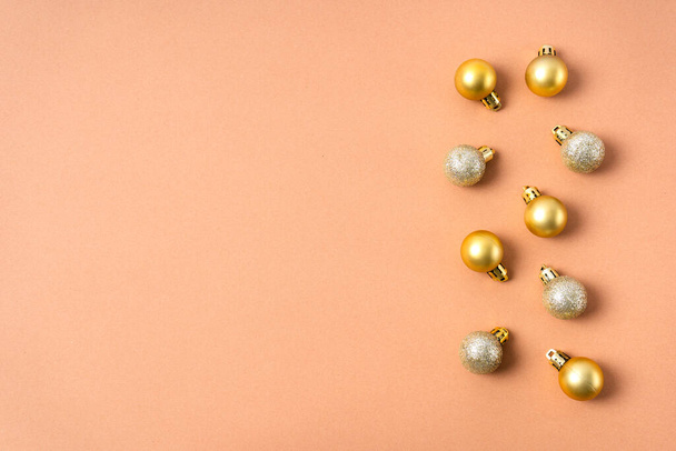 Zlaté třpytivé koule na vánočním stromečku jsou rozloženy v řadě na béžovém pozadí. Vánoční ozdoby. Kopírovat prostor - Fotografie, Obrázek