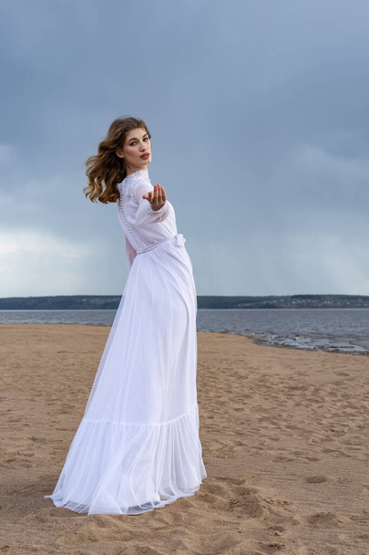 Happy young girl in a white dress on the sandy shore. Thunder Sky  - Foto, Imagen