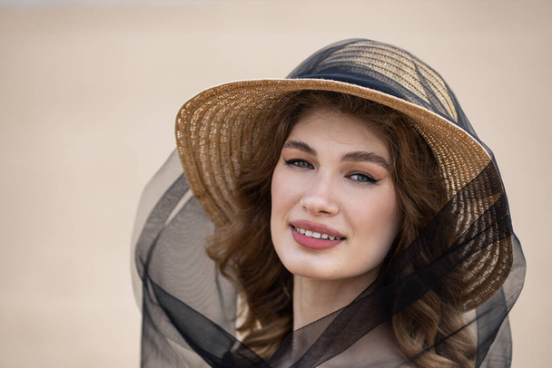 Щаслива дівчина в солом'яному капелюсі і в чорній сукні на березі річки. Грім на небі  - Фото, зображення