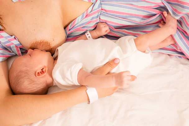 The mom is breastfeeding her newborn baby on the bed - Foto, afbeelding
