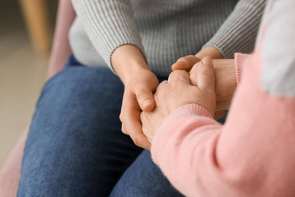 Young woman holding hands of grandmother at home - Photo, Image