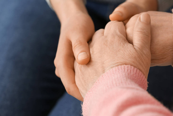 Young woman holding hands of grandmother, closeup - Фото, изображение