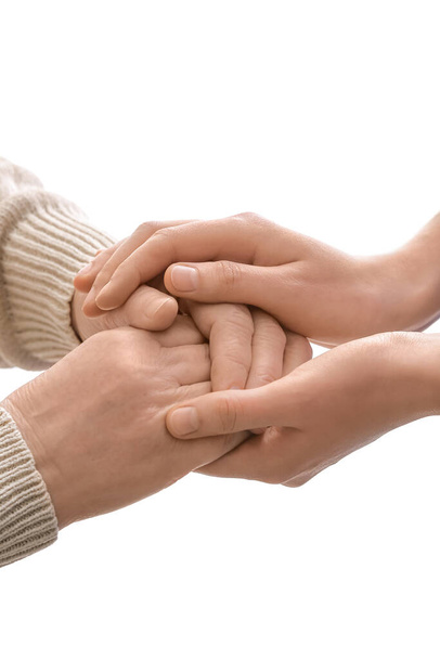 Young woman holding hands of grandmother on white background - Photo, Image