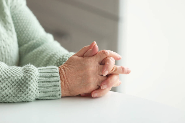 Χέρια ηλικιωμένης γυναίκας που κάθεται στο τραπέζι - Φωτογραφία, εικόνα