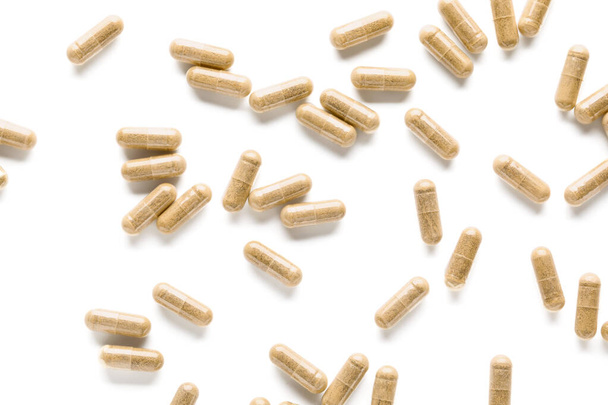 Vitamine K pillen verspreid over witte achtergrond - Foto, afbeelding