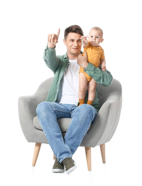 Mladý otec s malým dítětem ukazuje na něco na bílém pozadí - Fotografie, Obrázek