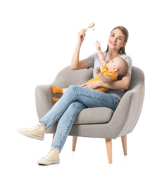 Jovem mãe com bebê pequeno e brinquedo sentado em poltrona no fundo branco - Foto, Imagem