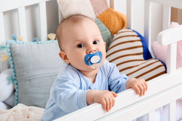Cute little baby boy with nibbler in crib - Photo, Image