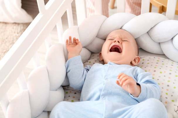 Плачущий маленький мальчик в кроватке - Фото, изображение