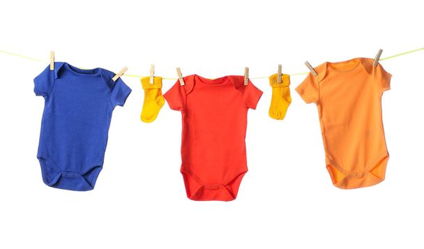 Seil mit bunten Baby-Bodys und Socken auf weißem Hintergrund - Foto, Bild