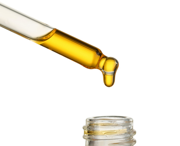 Goteo de aceite esencial de la pipeta en botella sobre fondo blanco, primer plano - Foto, Imagen