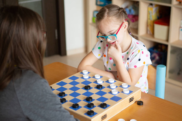 Menina com Síndrome de Down jogando damas - Foto, Imagem