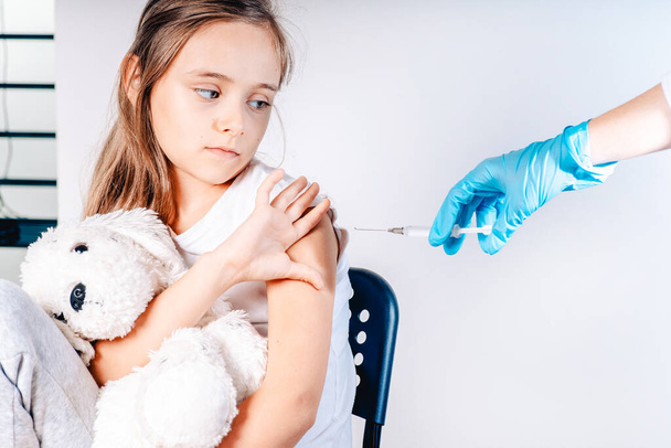 Vaccinations for children. The child was given a vaccine.Female doctor or nurse trying to give shot or vaccine against virus to a scared patient. Angry and distrustful patient refuses to receive it. - Photo, Image
